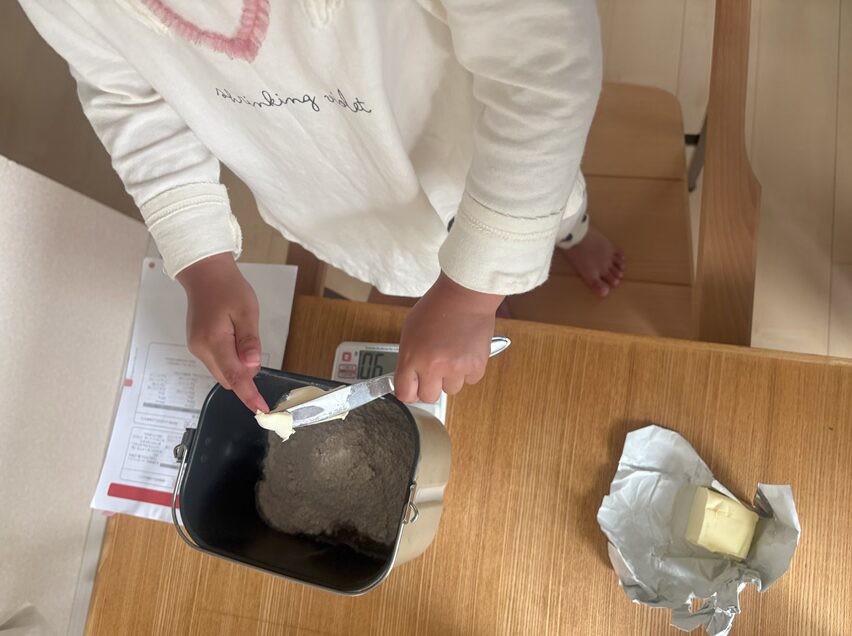 ホームベーカリーでパンを焼くために、計量してくれている子ども
