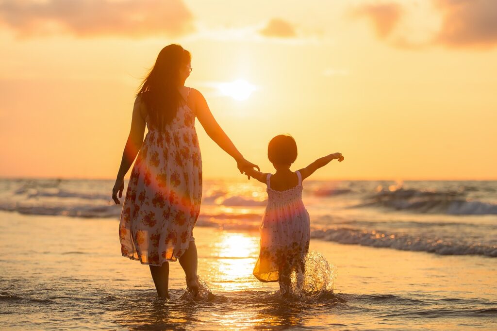 親子が浜辺で手をつなぐ後ろ姿